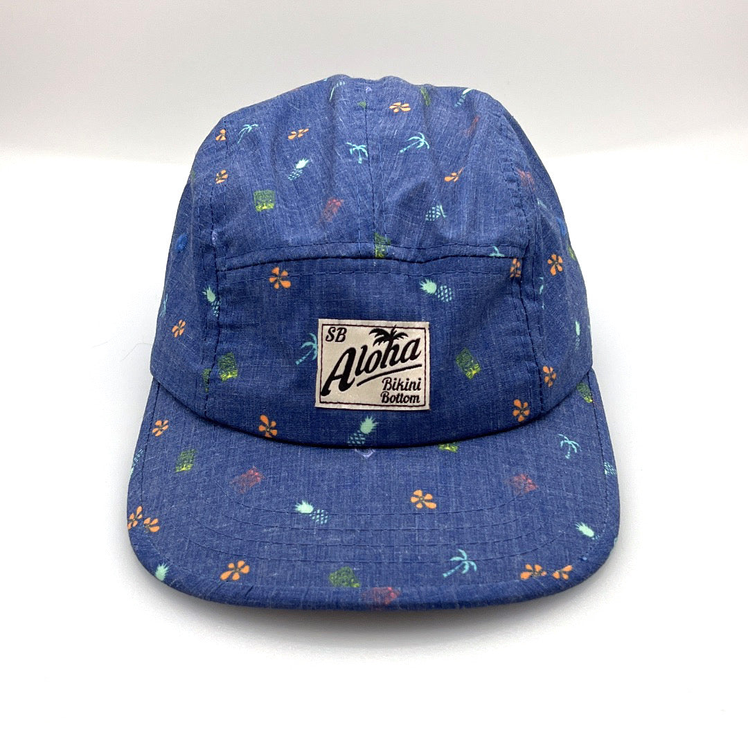 Blue Aloha 5 Panel Hat with little colored palm trees, pineapples and flowers, white background.