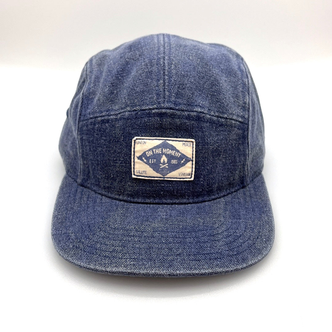 Blue denim Clakllie 5 Panel Hat with "On The Moment" logo on the front panel.