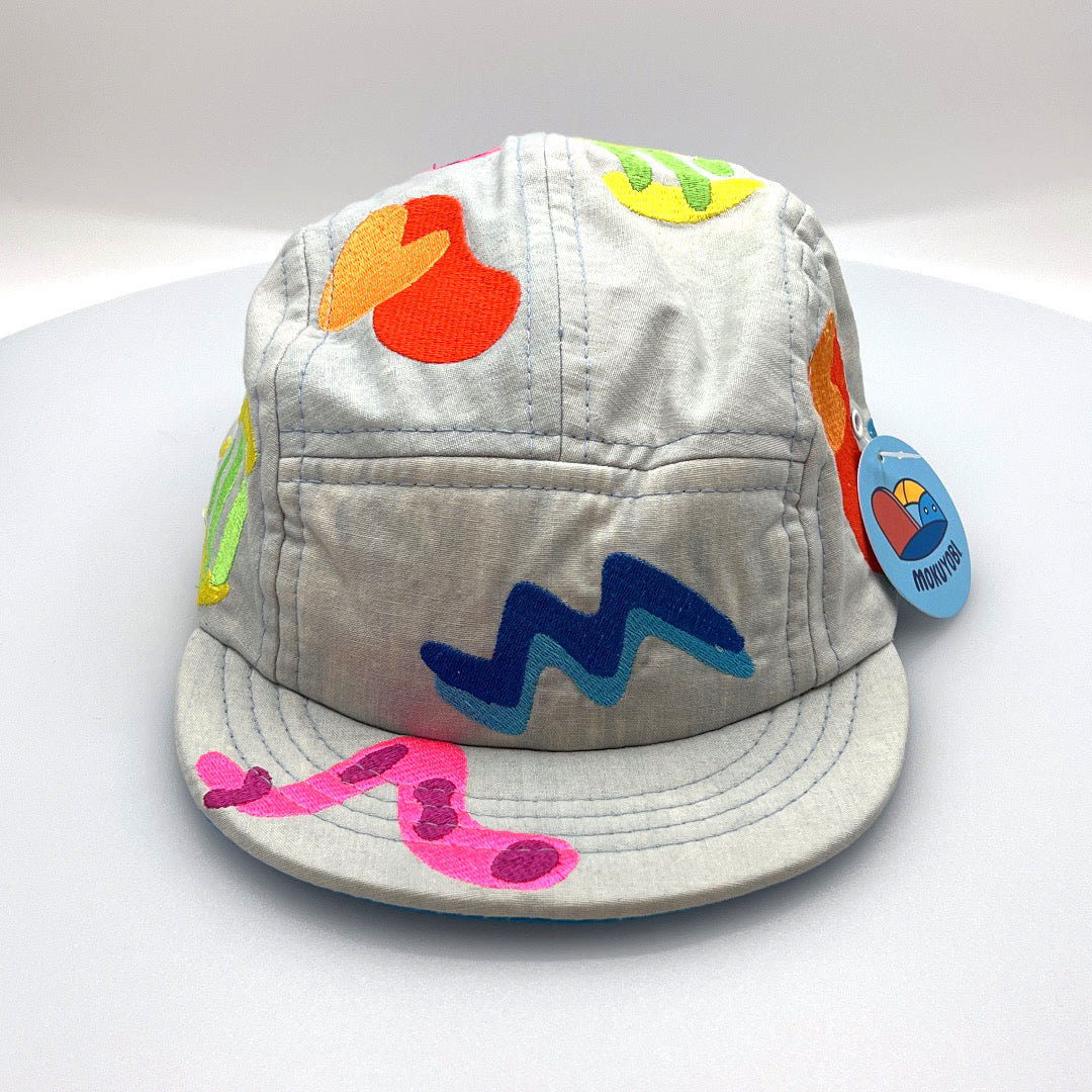 Grey MokuYobi with multi colored embroidered shapes, with white background.