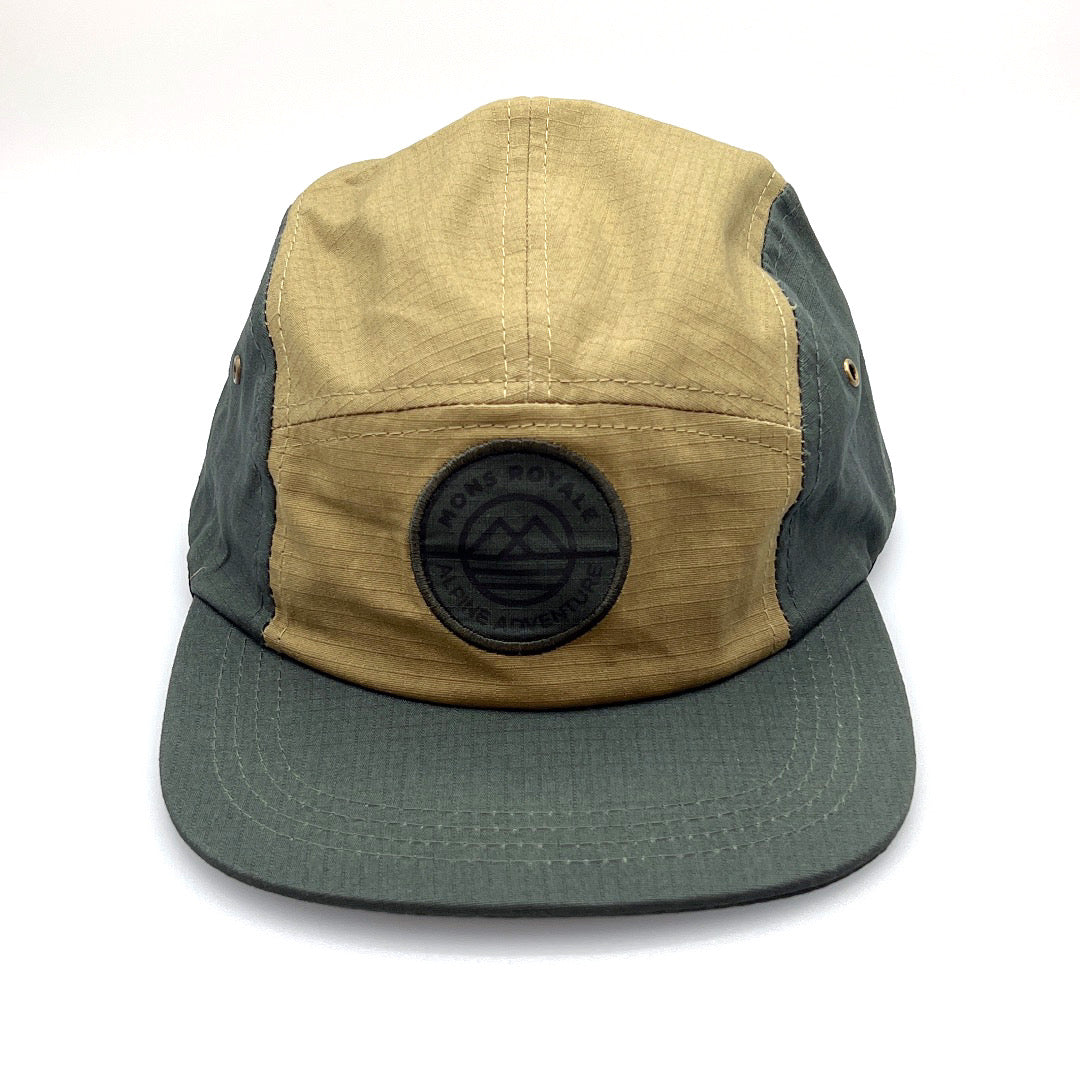 Dark green and tan Mons Royale Alpine Adventure 5 panel hat, with white background.