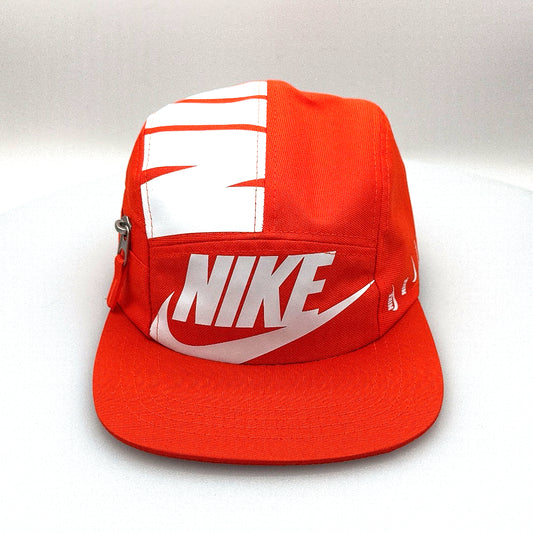 Orange and white NIKE shoe box bag upcycled to a 5 Panel Hat, zipper on right side panel, with white background.