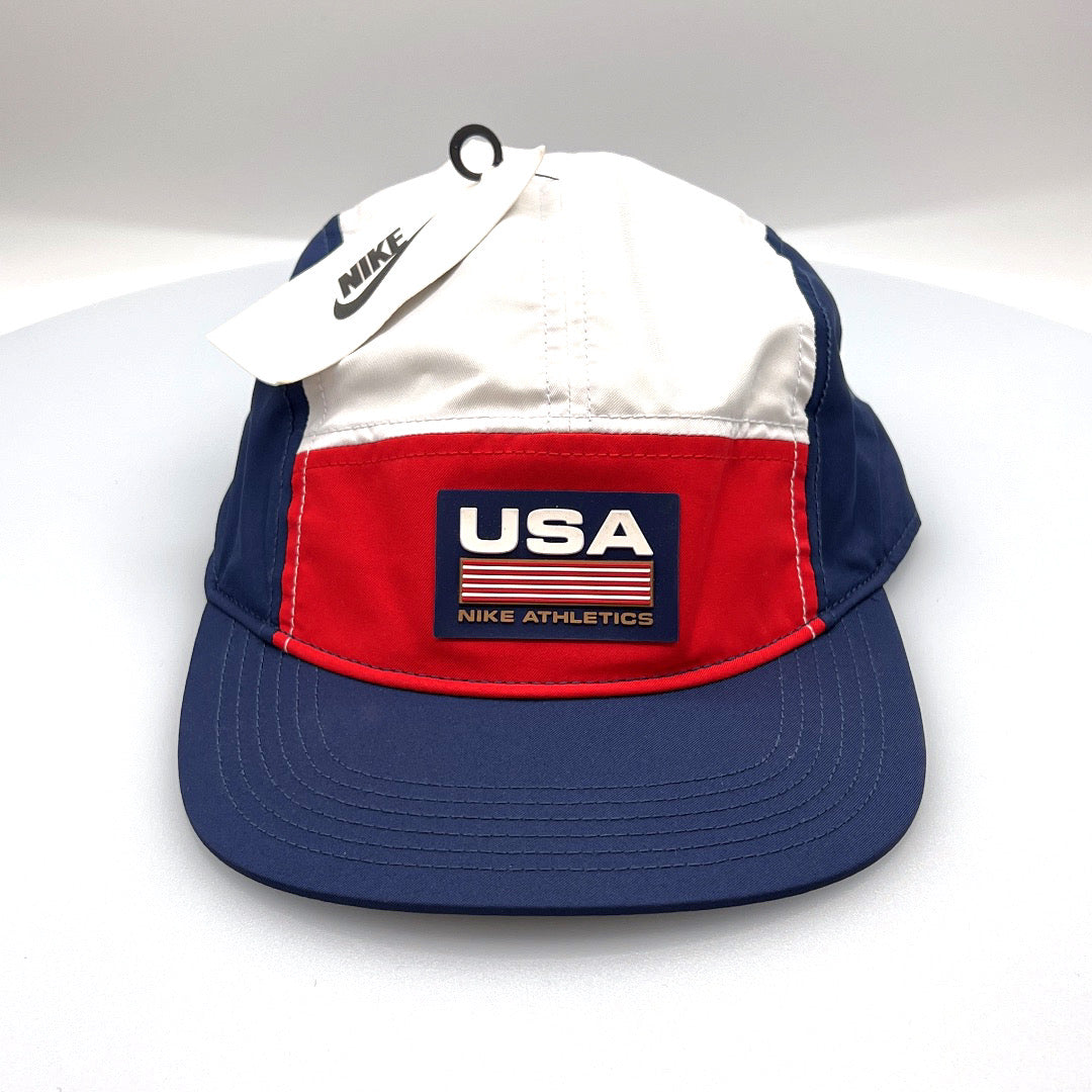 Red, white and blue USA NIKE Athletics 5 Panel Hat, rubber logo on front, with a white bachground.