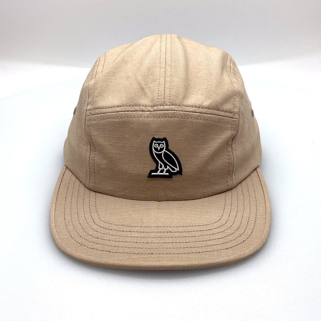 khaki OVO 5 Panel Hat, rubber OWL logo on front, with a white background.