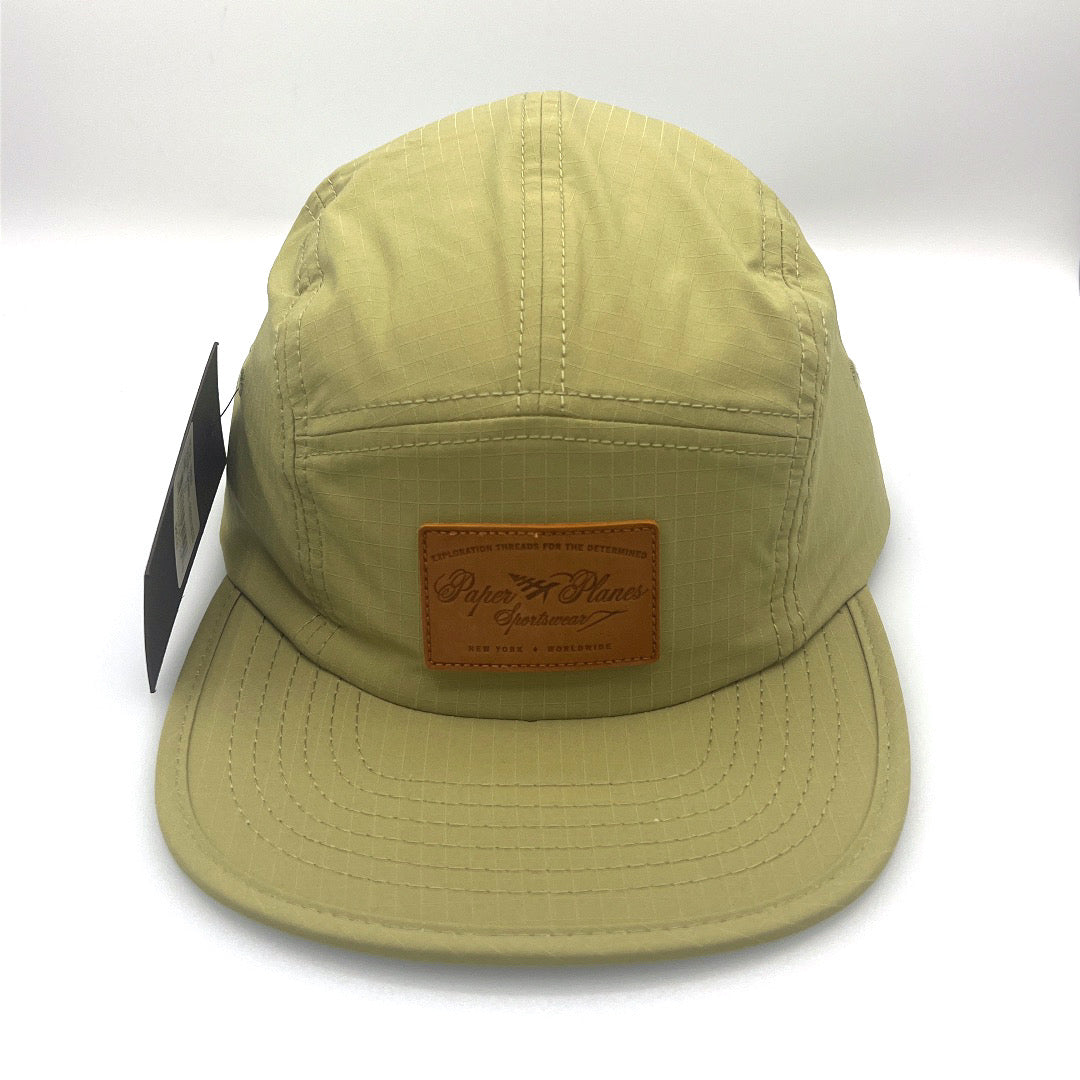 Nylon olive green Paper Planes 5 Panel Hat, leather logo on the front,with a white background.