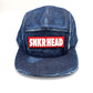 Distressed blue denim SNKRHEAD 5 Panel Hat, rubber logo on the front, with a white background.