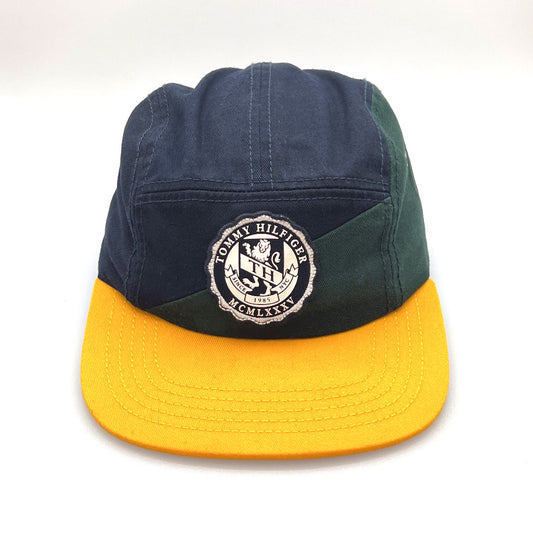 Yellow, green and navy Tommy Hilfiger 5 Panel Hat, big white logo on the front, with a white background.