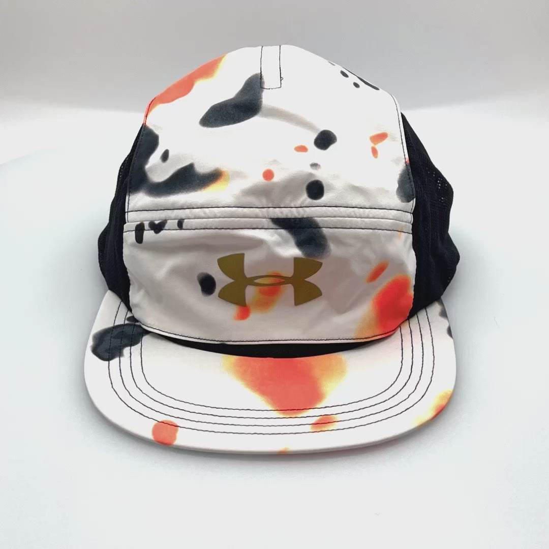 Spinning orange, white, black Under Armour 5 Panel Hat, gold logo on the front, with a white background.