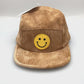 Spinning tan corduroy GuanGu 5 Panel Hat with yellow smiley face on the front panel.