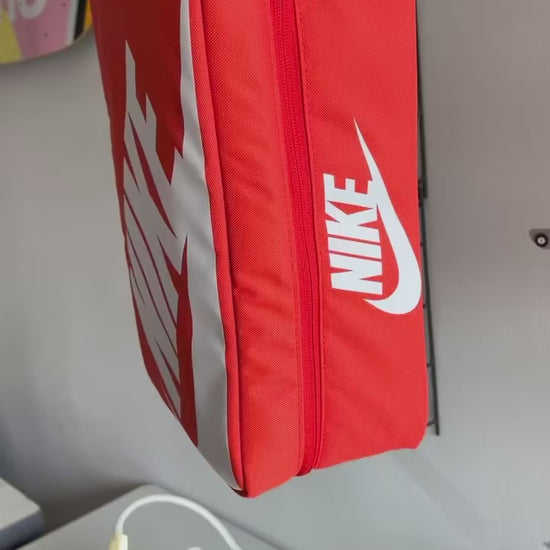 The making of a orange and white NIKE shoe box bag upcycled to a 5 Panel Hat, zipper on right side panel, with white background.