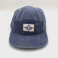 Spinning Blue denim Clakllie 5 Panel Hat with "On The Moment" logo on the front panel.