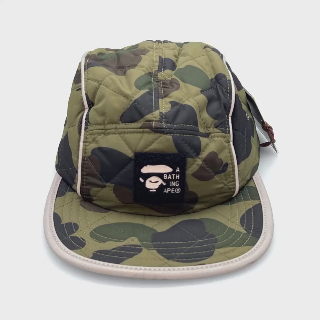 Spinning Green camo BAPE 5 Panel Hat with unique dark green stitching, white background.