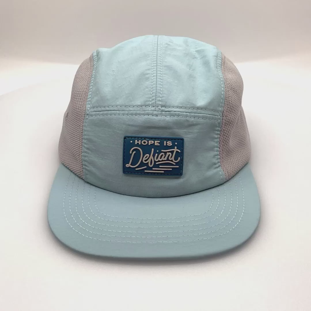 Spinning Baby blue Defiant 5 Panel Hat with grey netting on side panels and rubber logo on the front.