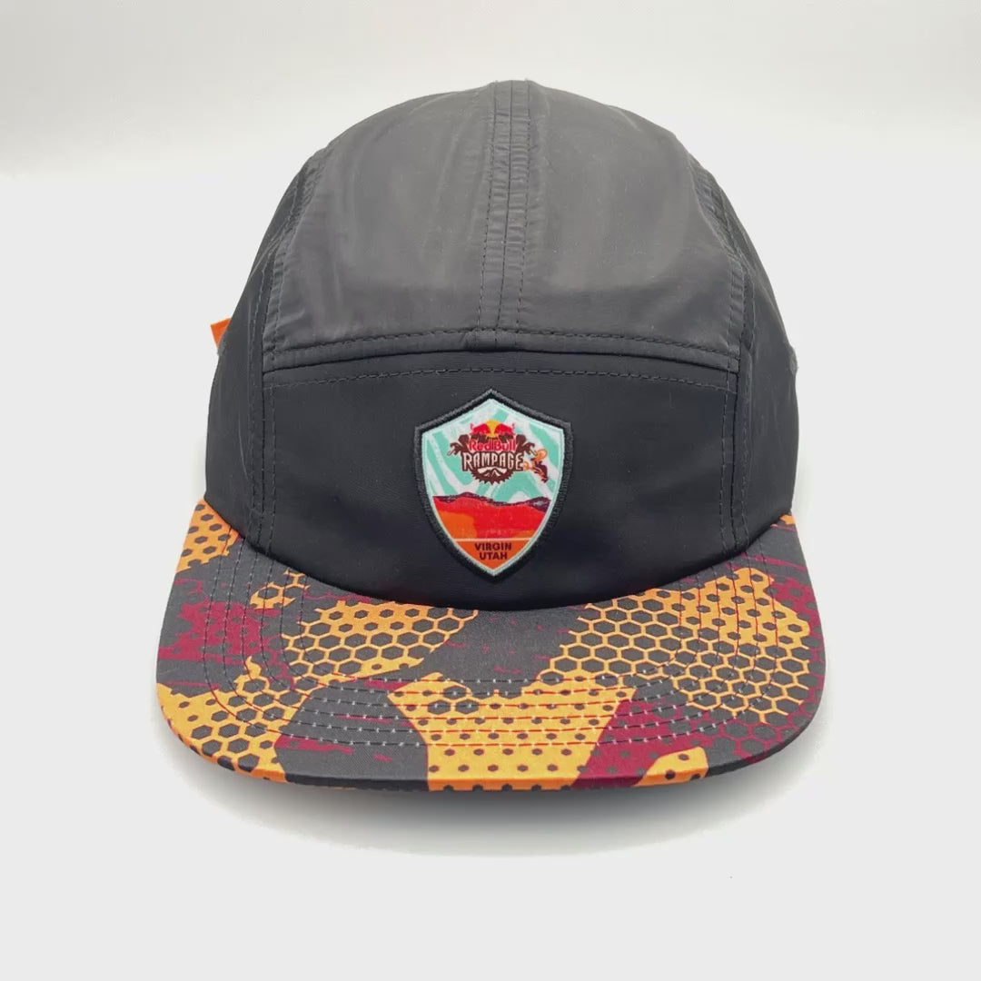 Spinning red, orange and black RedBull Rampage 5 Panel  Hat, Virgin Utah logo on the front, with a white background.