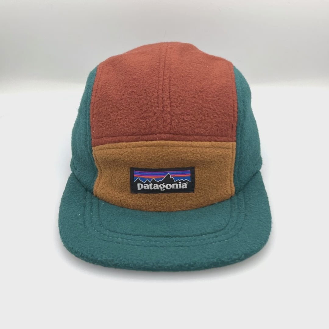 Spinning brown, tan and cyan Patagonia fleece 5 Panel Hat upcycled, iconic logo on the front, with a white background.