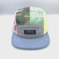 Spinning camo, blue, green, grey and pink patchwork Polo 5 Panel Hat upcycled, iconic Polo RL logo on the front, with a white background.