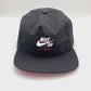 Spinning Nike Air SB Black 5 Panel Hat, Nike Air SB logo on front, with white background.